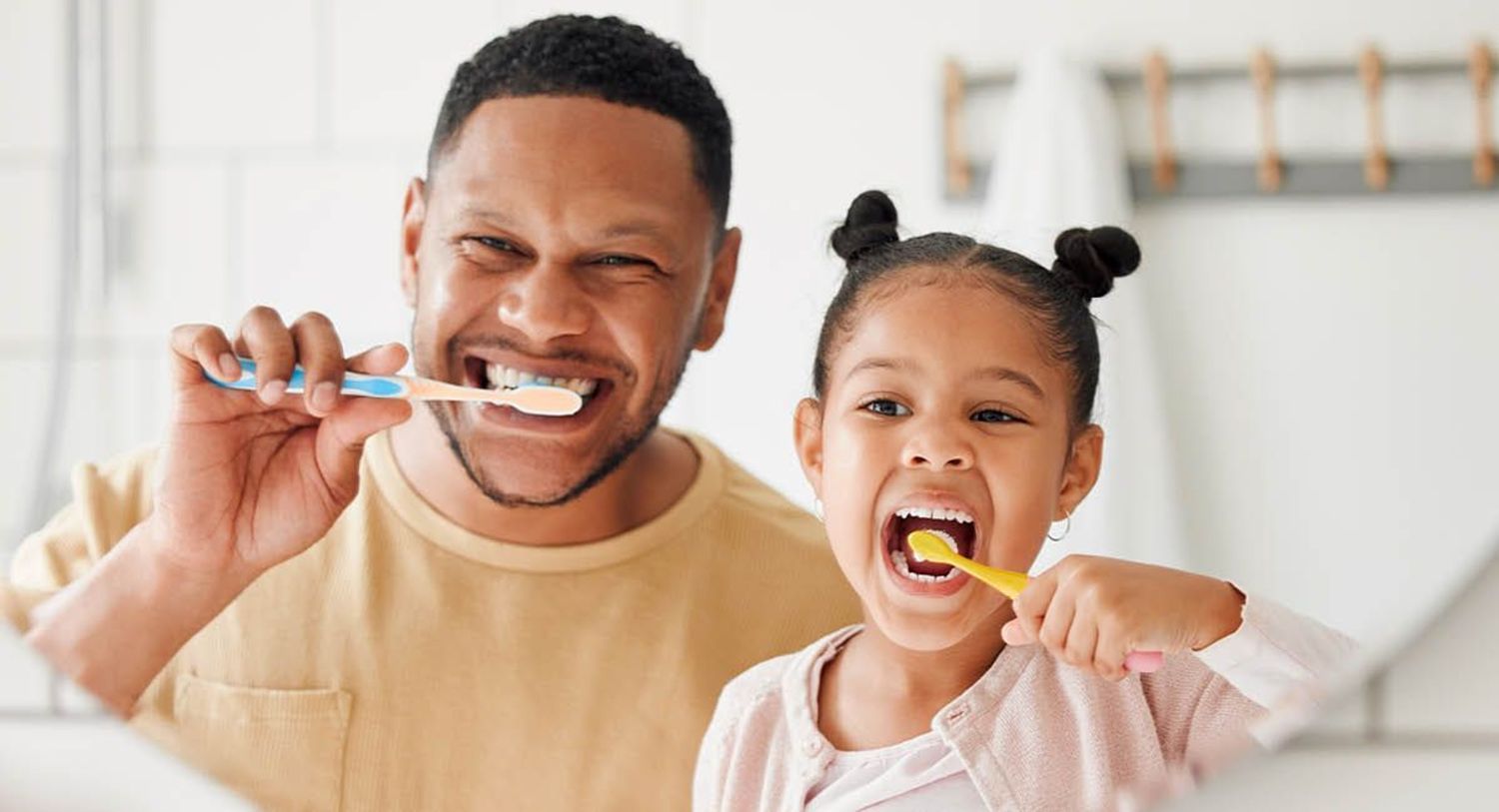 Father and daughter brushing teeth and smiling