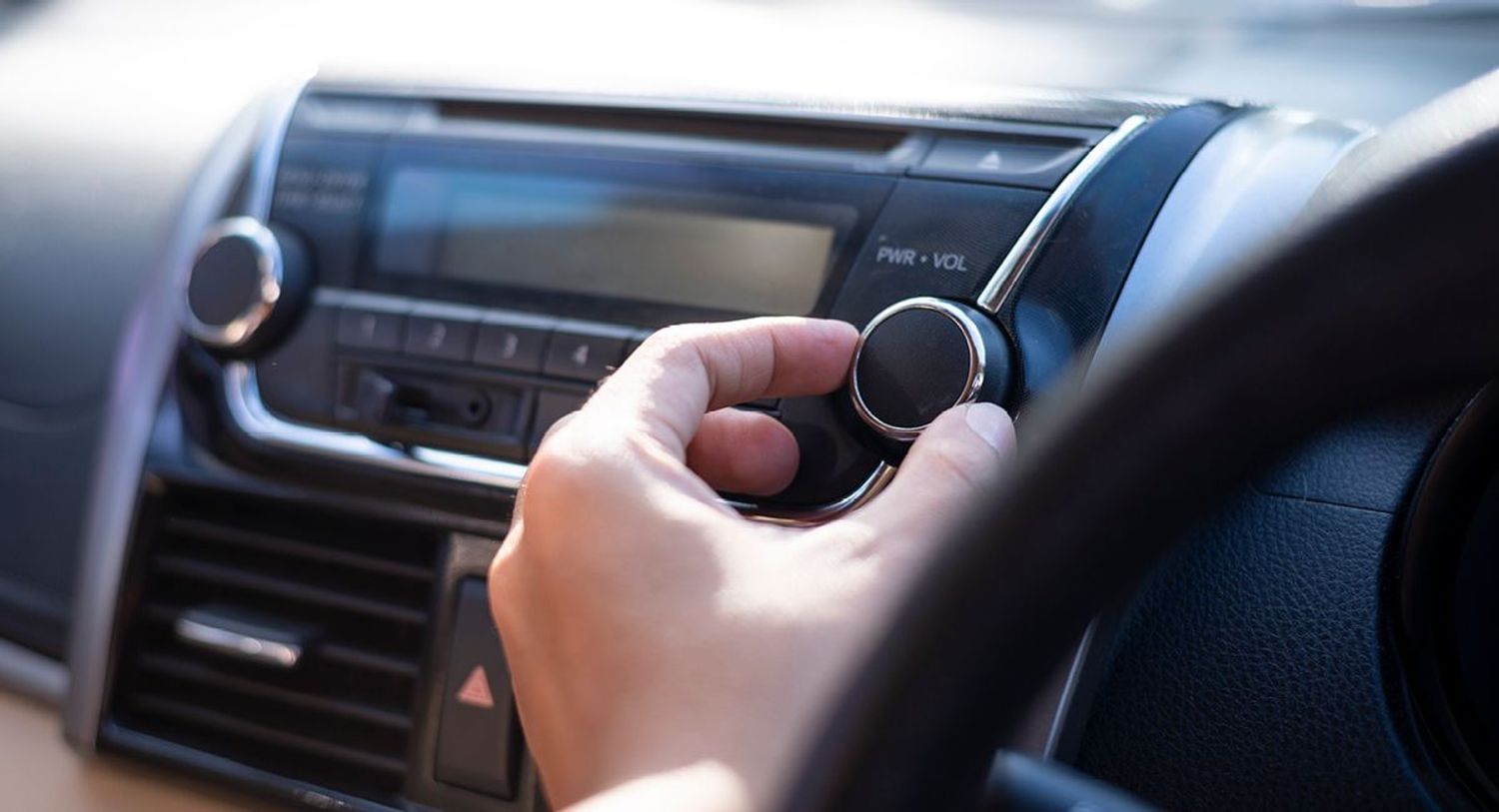 Fingers adjusting the dial on a car radio