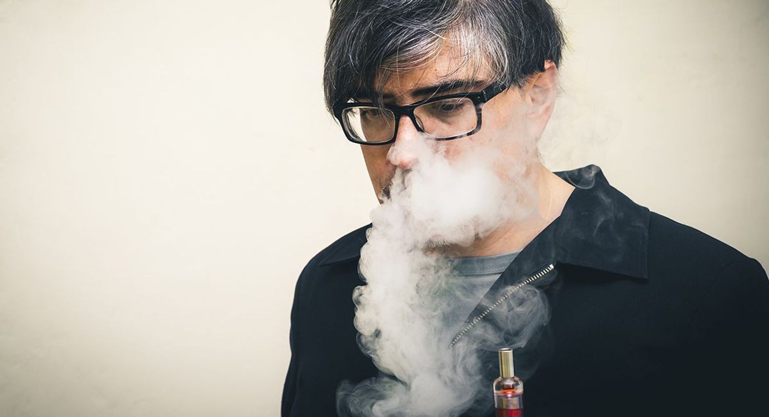 Man using a vape surrounded by smoke