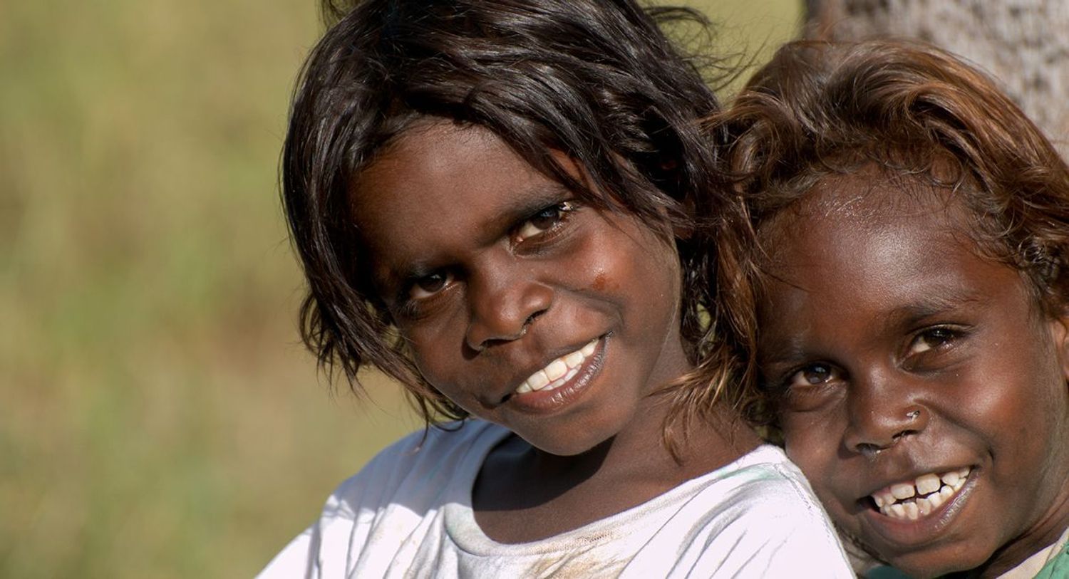 Two smiling Indigenous children looking at the camera