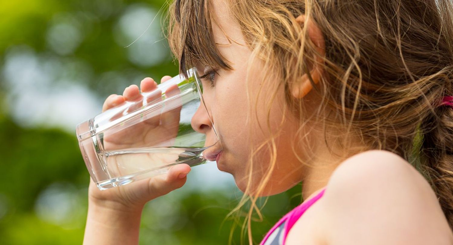 Girl drinking from a glass of fluoridated tap water