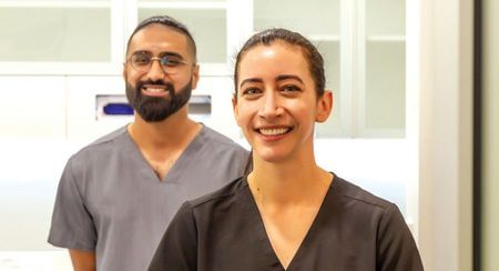 Smiling dental staff - one man and one woman - in scrubs