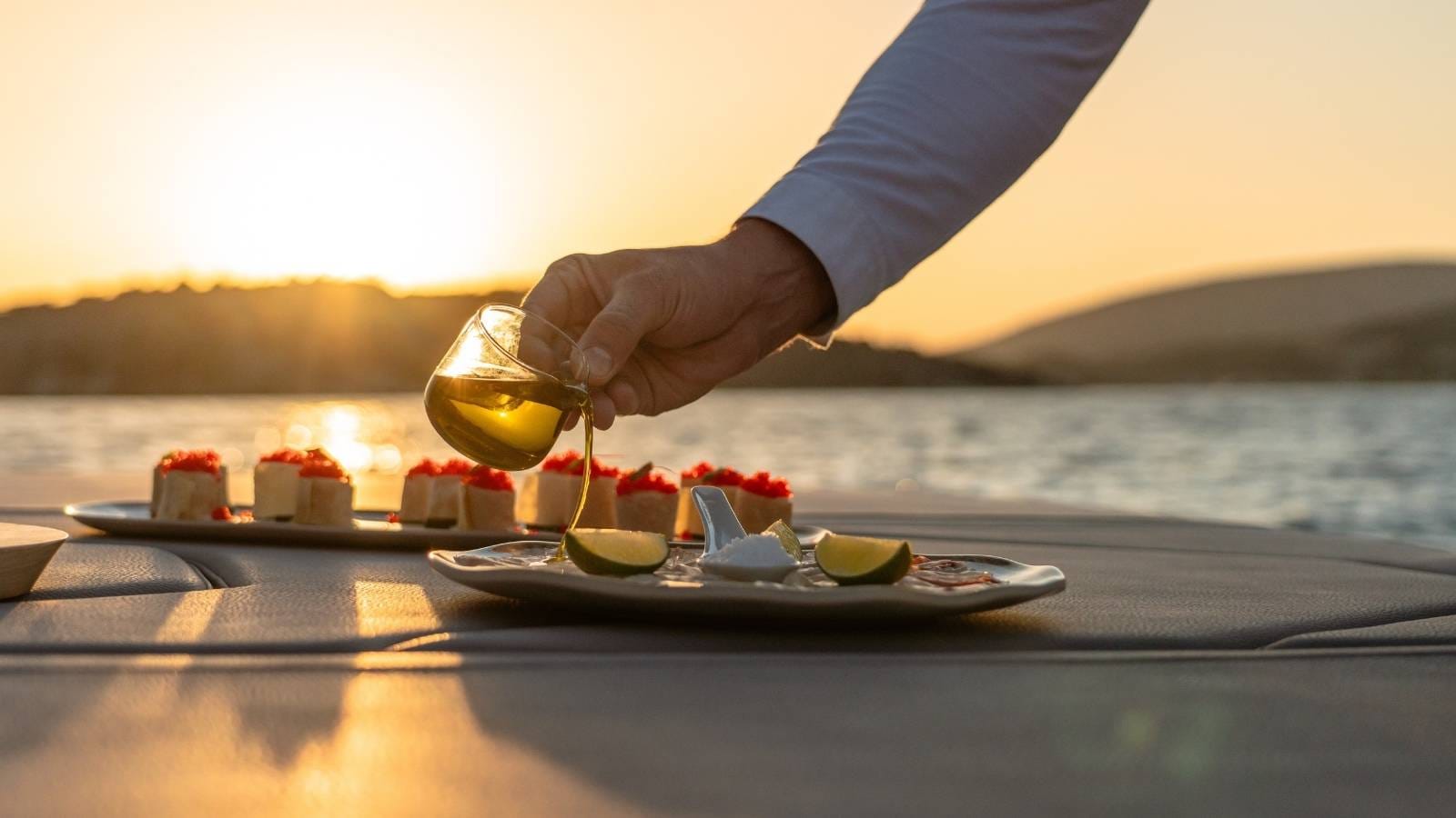 close up on chef's hand serving on yacht during sunset