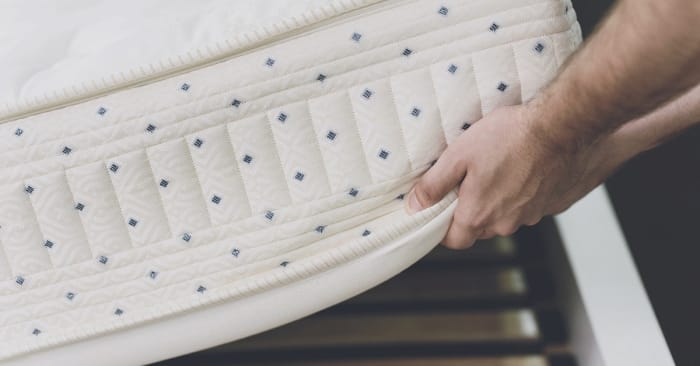 
                    Person adjusting a mattress cover, emphasizing bed bug prevention measures related to Convectex heat treatment solutions.
                          