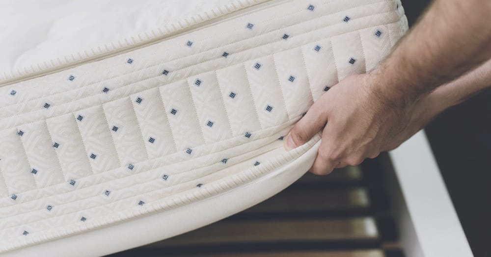 
                Person adjusting a mattress cover, emphasizing bed bug prevention measures related to Convectex heat treatment solutions.
                      