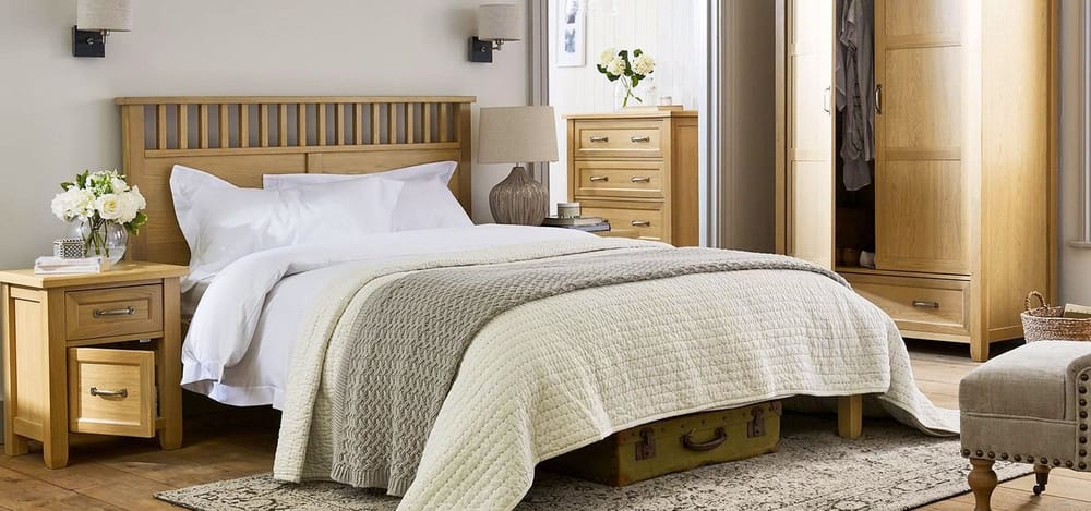 Cozy bedroom setup featuring a wooden bed frame with white bedding, bedside table with flowers, and storage furniture, suitable for apartment bed bug heat treatment preparation.