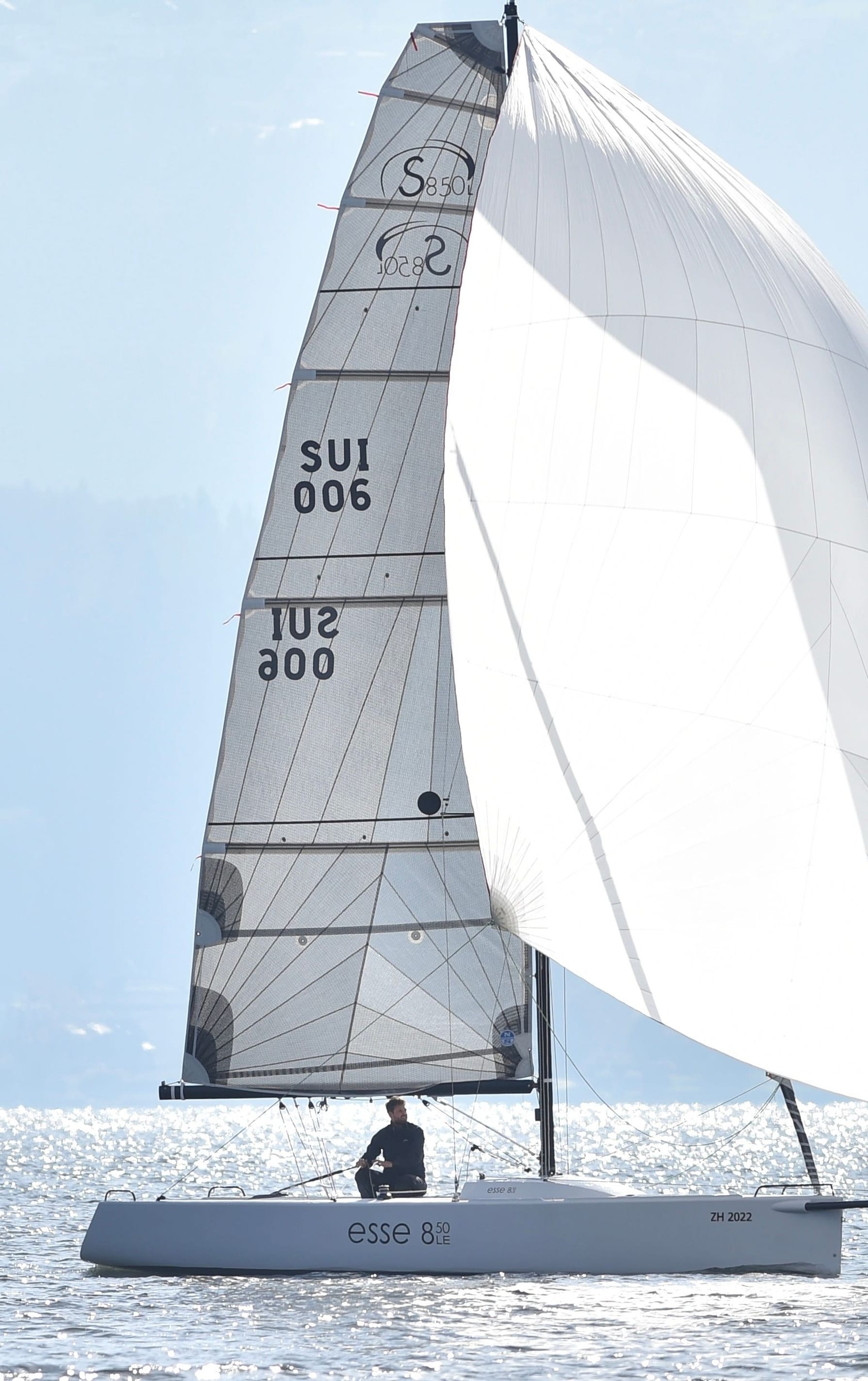Eine Esse 850 LE in voller Pracht auf ruhigem Wasser, vor einer Bergkulisse am Zürisee. Jetzt mehr über die Esse 850 LE erfahren auf esseboats.ch