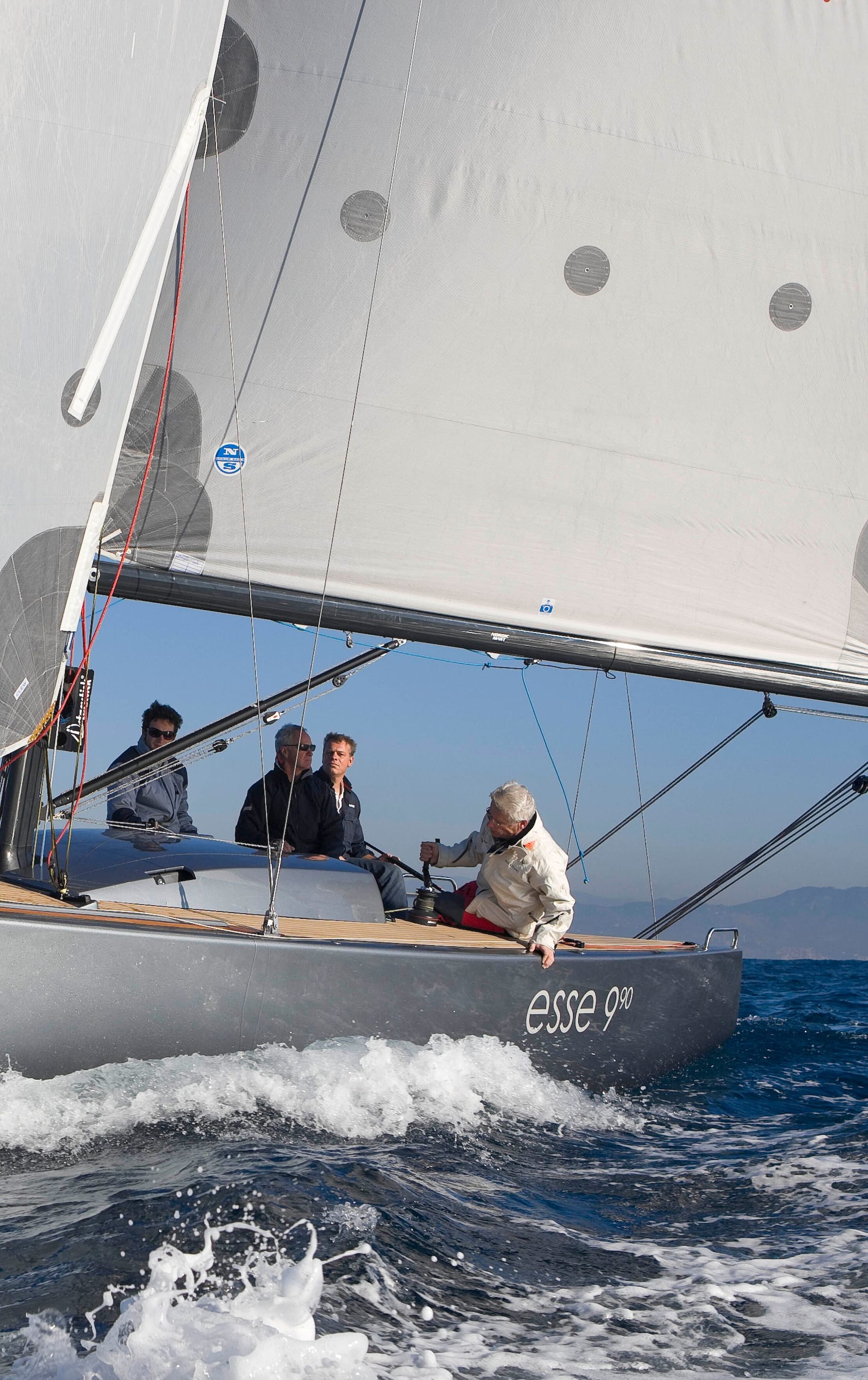 Esse 990 023: Ein Segelboot der Marke 'Esse' segelt mit hoher Geschwindigkeit auf tiefblauem Wasser, mit einem deutlichen Fokus auf das Segel mit der Aufschrift 'Esse'. Für weitere Informationen besuchen Sie esseboats.ch.