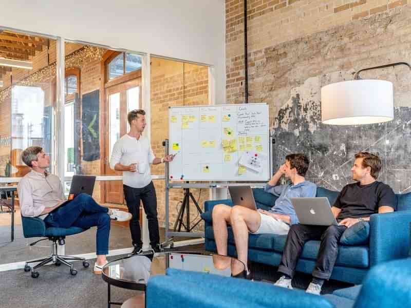 Mensen bespreken reisplannen rond een whiteboard in een kantooromgeving.