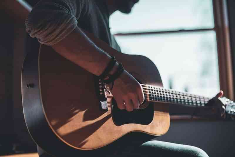 Man speelt gitaar en geniet van muzikale reisavonturen.