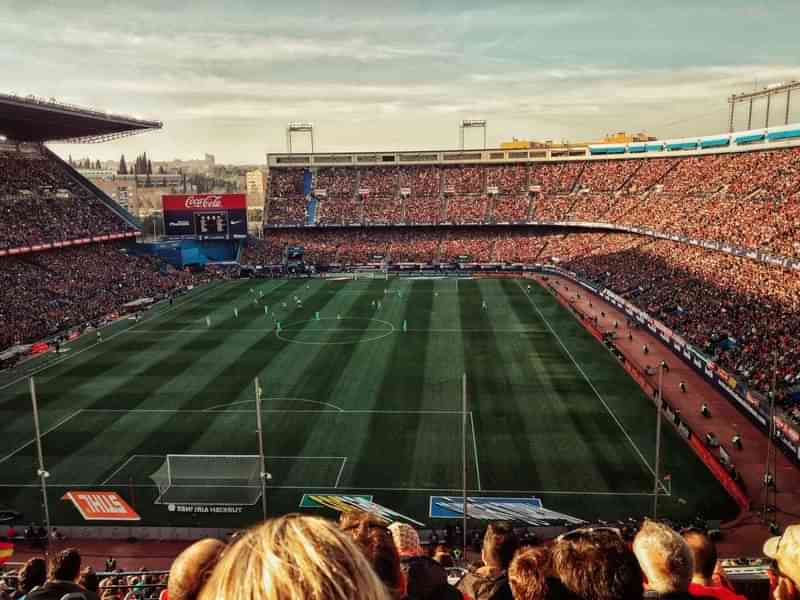 Voetbalwedstrijd in een groot stadion met veel toeschouwers.