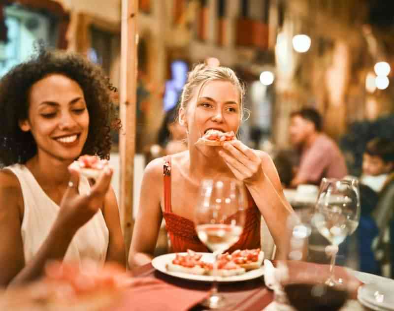 Friends enjoying local cuisine at an outdoor restaurant while traveling.