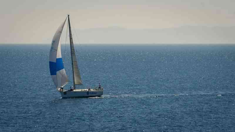 Zeilboot op zee met heuvels op de achtergrond, serene omgeving.