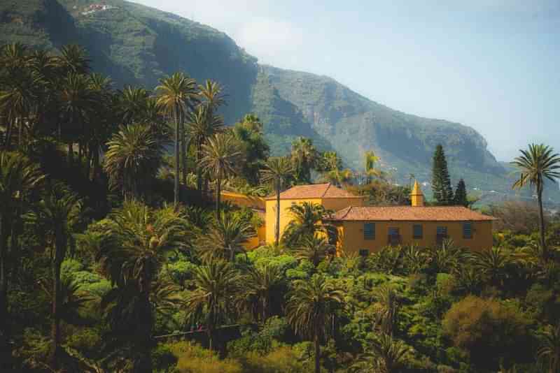 A mountain landscape with a yellow house and lush green vegetation.