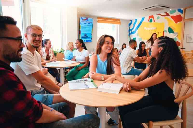 Students conversing in a lively language school setting with colorful decor.