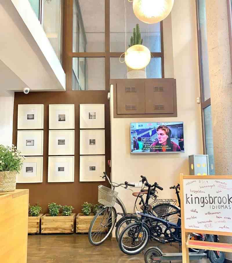 Language school with bikes, TV, plants, and sign, "kingsbrook Idiomas."