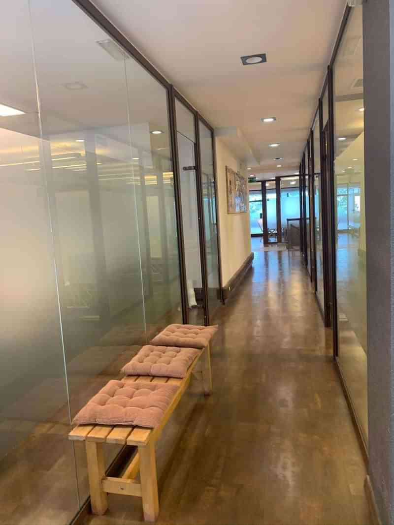 Modern language school lobby with glass-walled classrooms and cushioned benches.