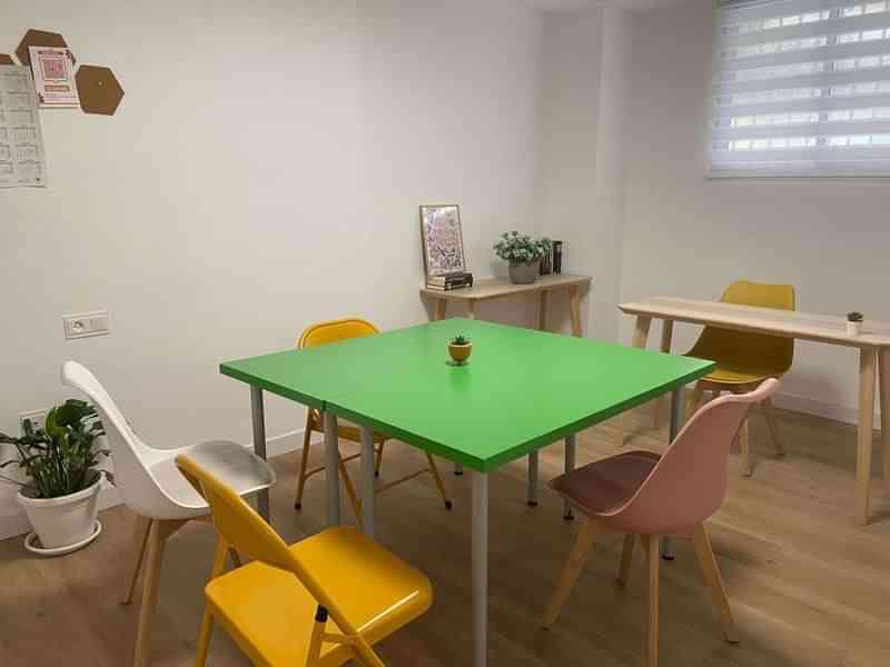 Language learning classroom with colorful chairs, green table, and study materials.