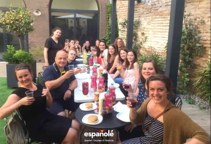 A group of people enjoying a meal outdoors, language immersion.