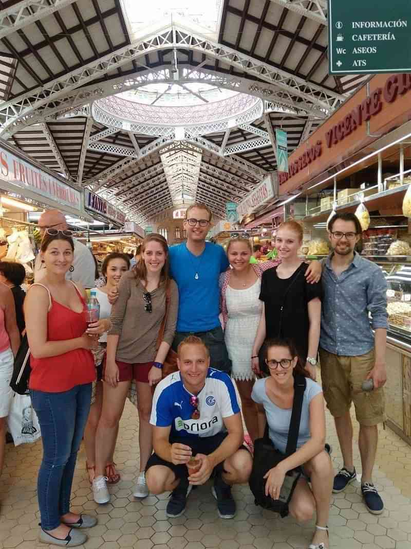 Groep toeristen in een overdekte markt, genieten van lokale cultuur en taal.