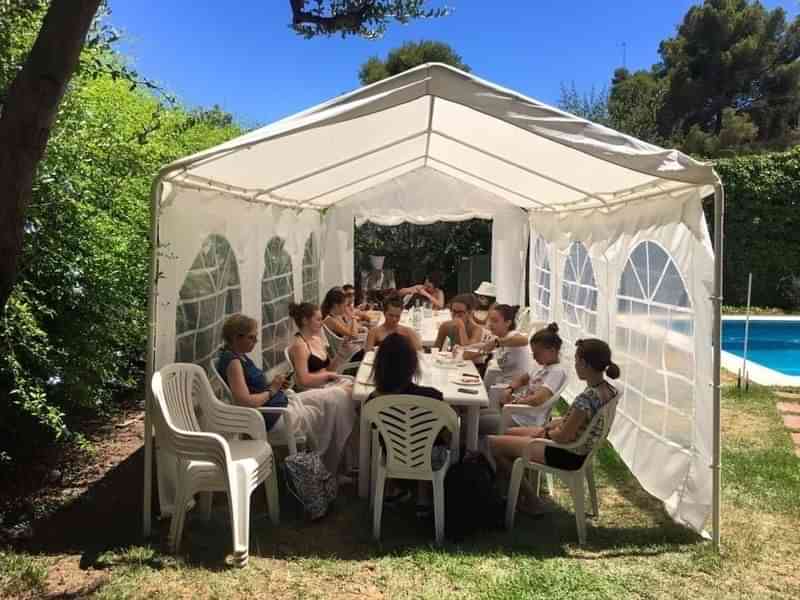 Taalreizigers genieten buiten van een groepsles in een zonnige tuin.