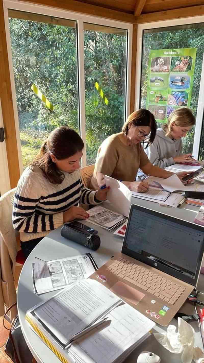 Studenten werken aan taalopdrachten in een zonnige studieruimte.