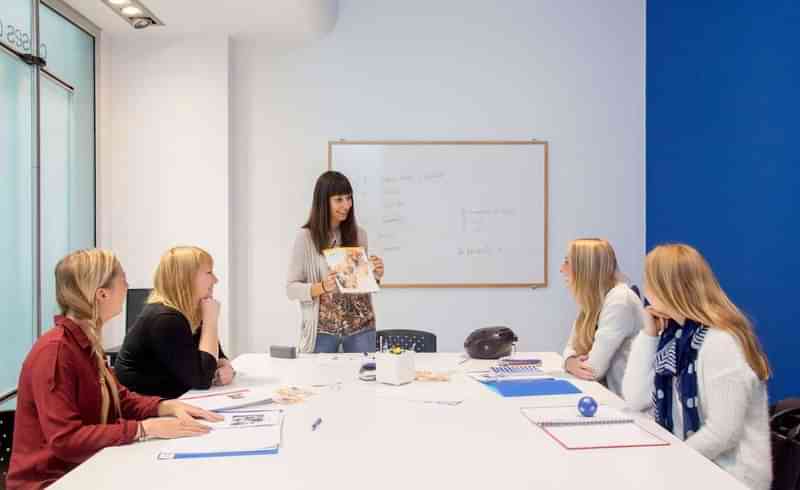 Docent geeft taalles aan een groep studenten in een klaslokaal.