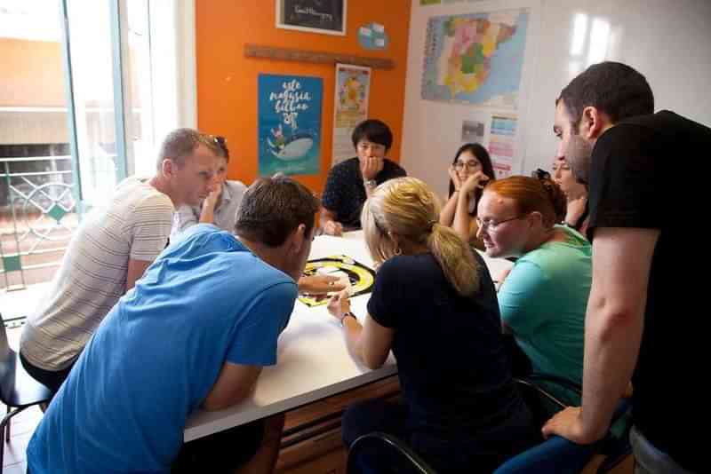 Groep studenten in taalles, gesprek en samenwerking in comfortabele klasomgeving.