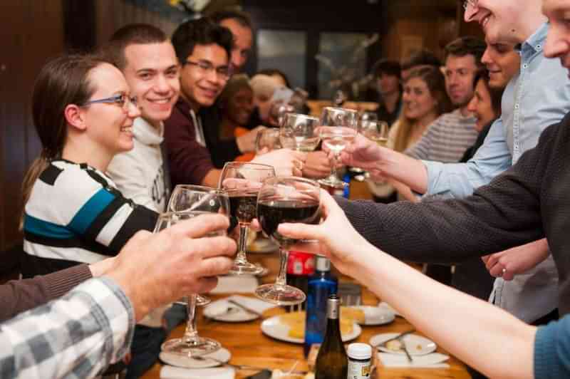 Groep mensen proost tijdens een diner, taaluitwisseling en cultuurervaring.