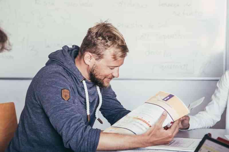 Man leest studiemateriaal in een klaslokaal, waarschijnlijk taalcursus.