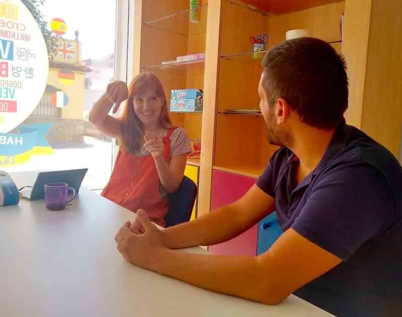 Studente en docent in taalschool tijdens interactieve les, kleurrijke omgeving.