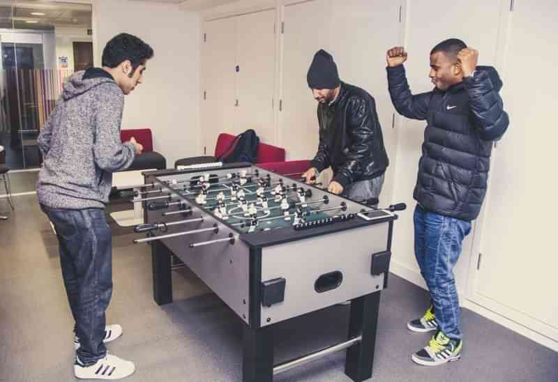 Studenten spelen tafelvoetbal in een gemeenschappelijke ruimte, gezelligheid alom.