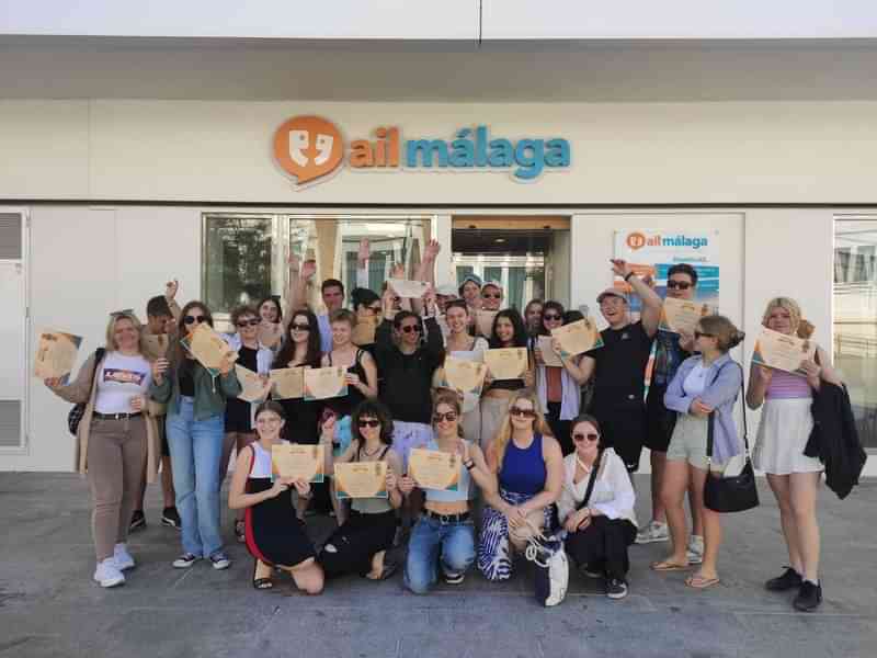 Group of students holding certificates in front of a language school.