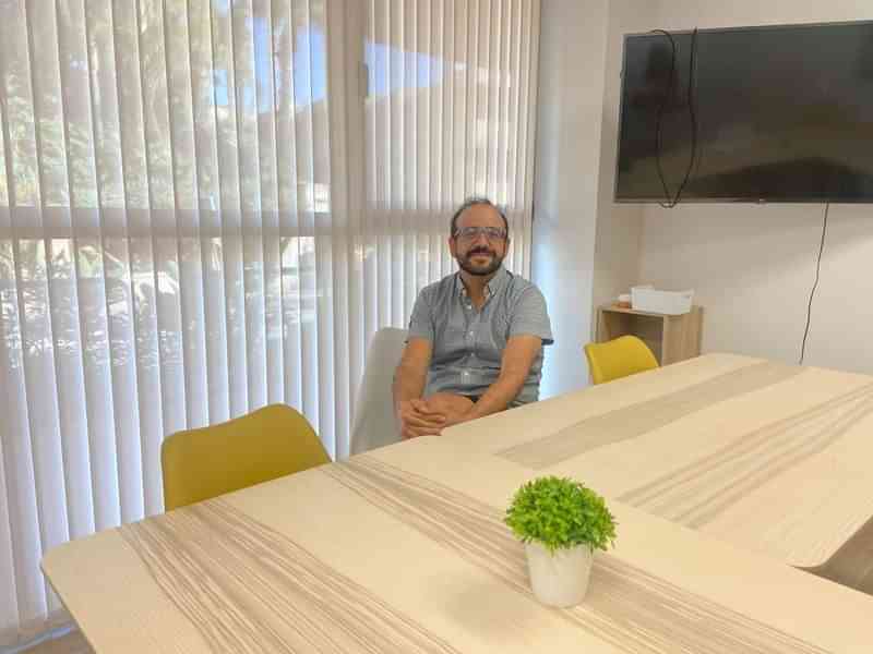 Man in vergaderruimte met tv en plant op tafel.