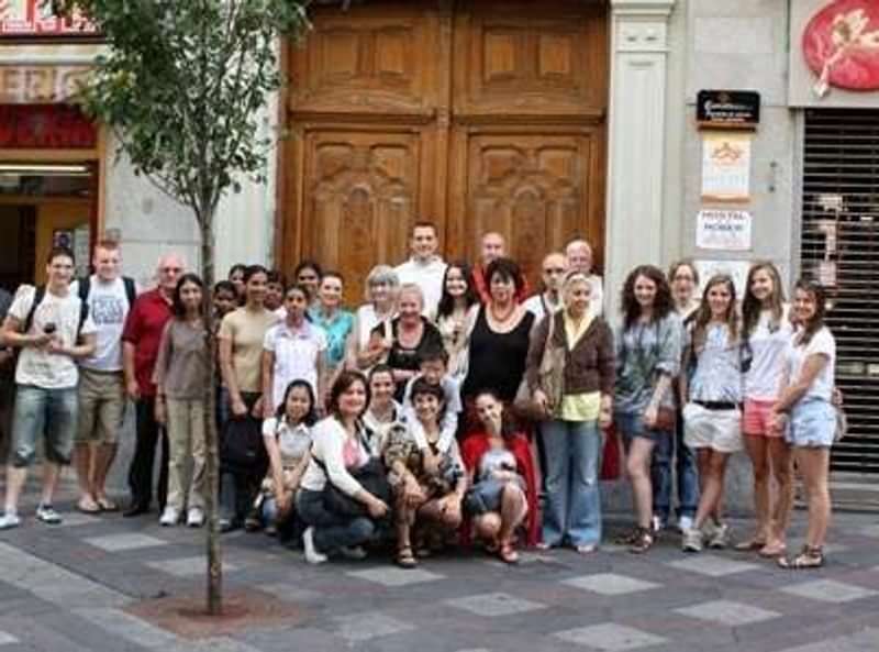 Group of travelers outside a language school, smiling and posing together.