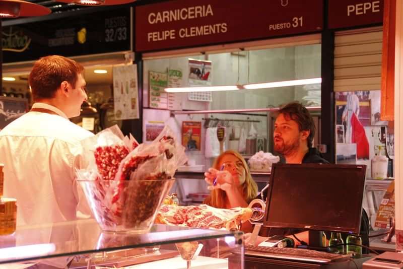 Tourists communicating in a local market stall with a vendor.