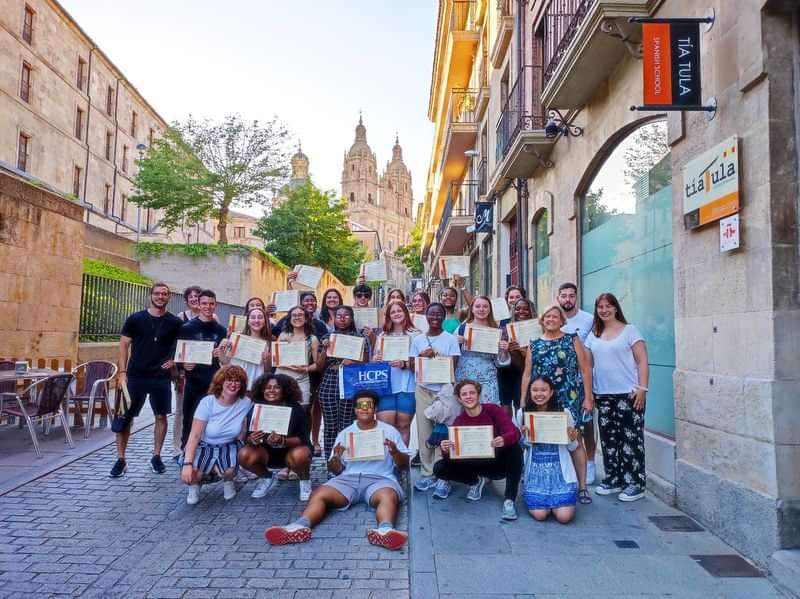 Group of students holding certificates, celebrating language course completion abroad.