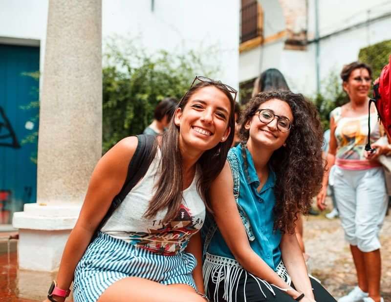 Two friends smiling outdoors, enjoying a cultural language travel experience.