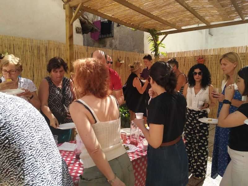 Gathering of travelers enjoying local food and conversation under a pergola.