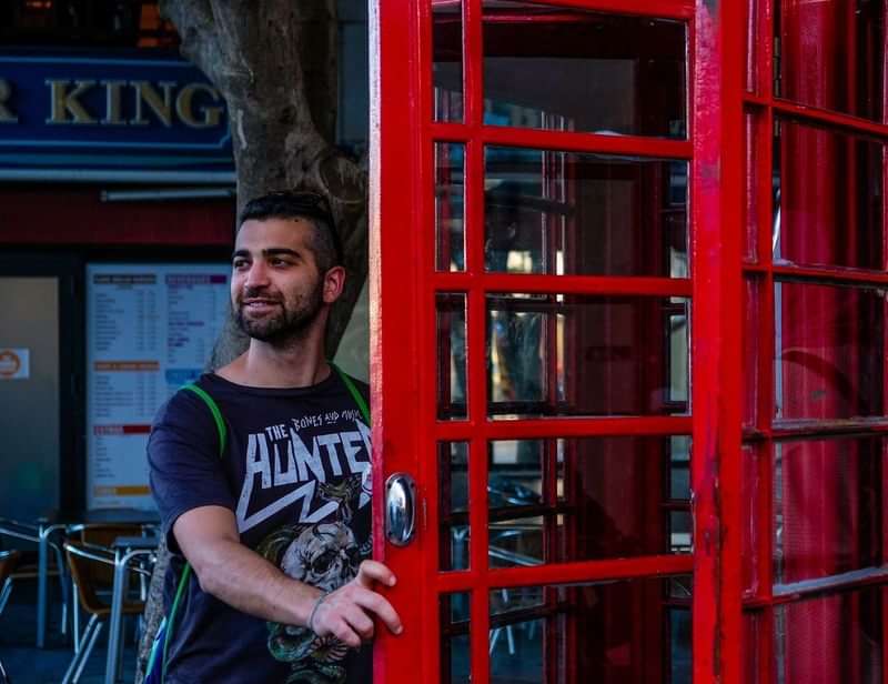 Man opent Engelse rode telefooncel tijdens taalreis.