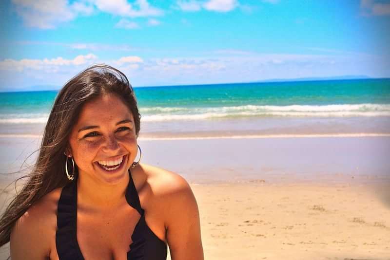 Smiling woman enjoying a sunny beach, possibly on language immersion trip.
