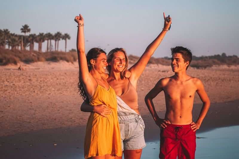 Friends at beach enjoying language travel, celebrating new experiences together.