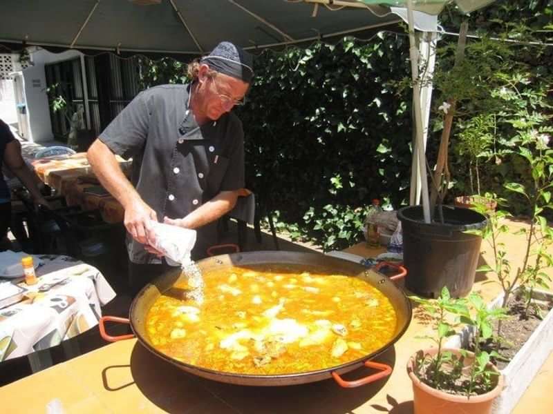 Chef preparing paella outdoors, showcasing Spanish culinary culture during language travel.