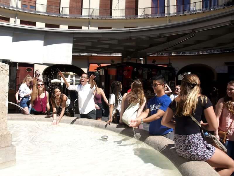 Studenten verzamelen zich rond een fontein tijdens een taalreiservaring in het buitenland.