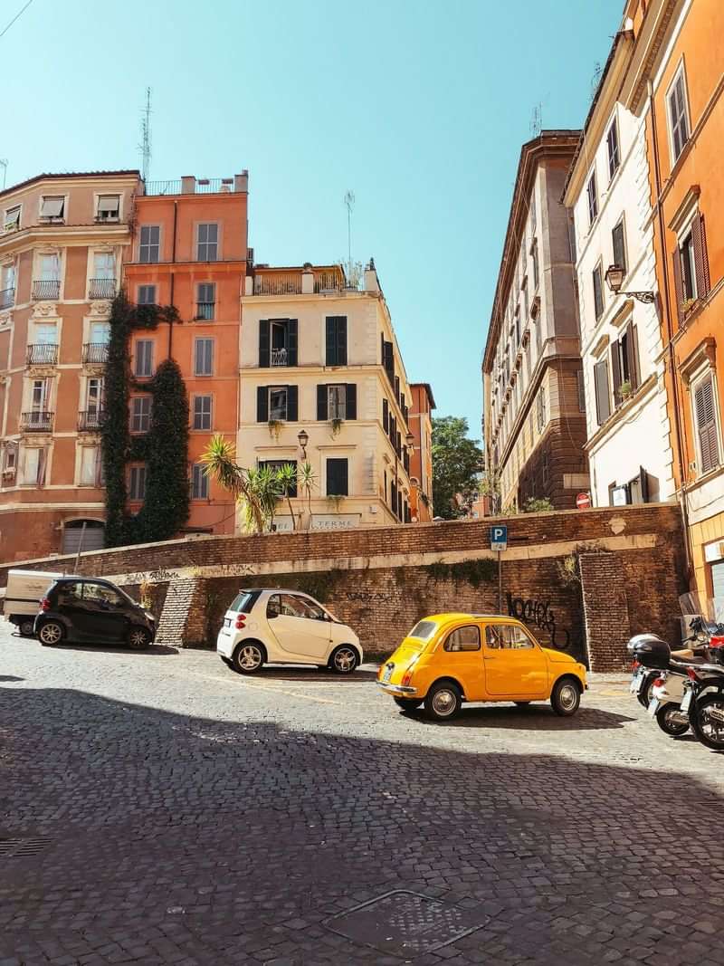 Historic European street with colorful buildings and small cars, charming locale.
