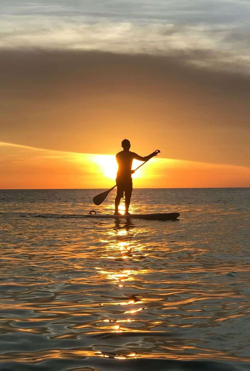 Paddleboarding at sunset, a perfect adventure for language learners.