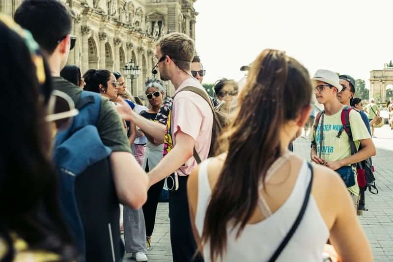Groep toeristen luistert naar gids tijdens rondleiding door historische stad.