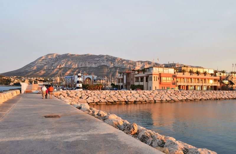 Seaside village with mountain backdrop, ideal for immersive language travel experience.