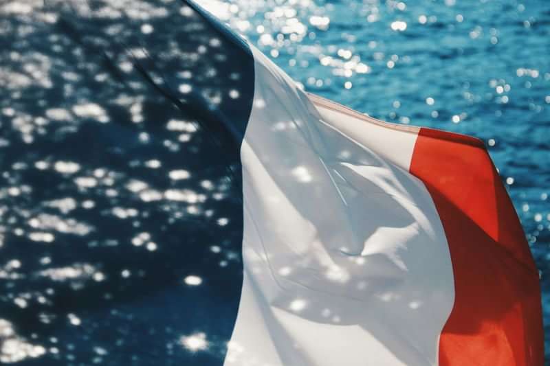 French flag by the sea, symbolizes travel to France.