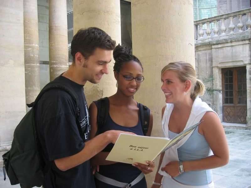 Drie studenten bekijken een boek tijdens een taalreis.